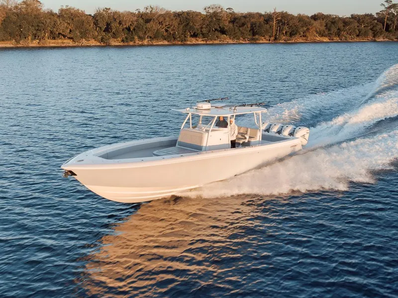 Slide: The Image of 2021 Contender 44 ST boat cruising on a calm lake with forested shoreline. - 12