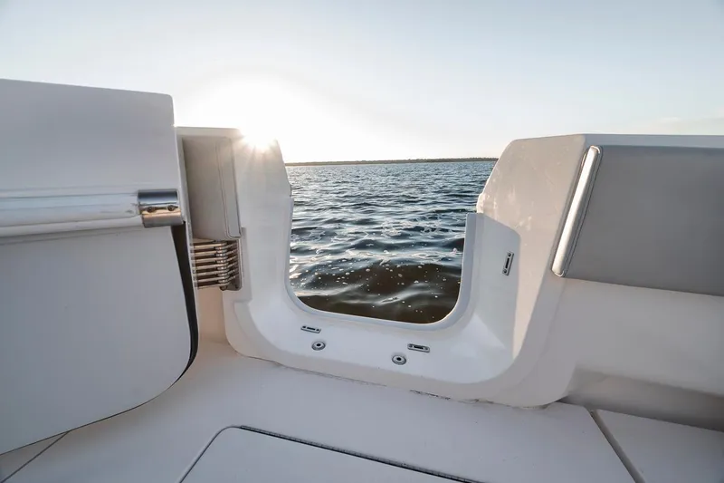 Slide: The Image of Contender 44 ST 2021 boat with open transom door, overlooking serene water at sunset. - 44