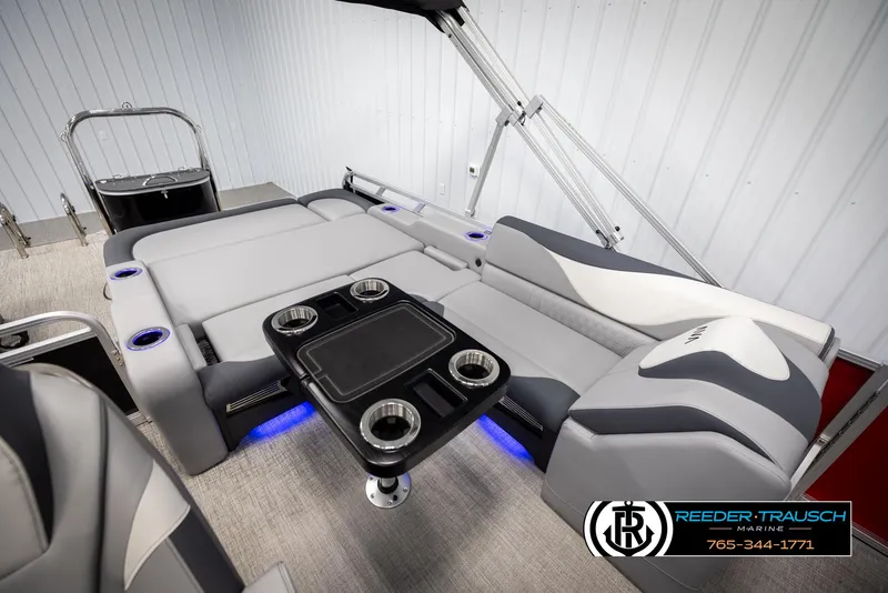 Slide: The Image of 2025 Avalon LSZ VRB boat interior with gray seating and cup holders, featuring blue LED lighting. - 26