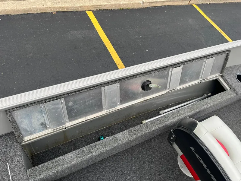 Slide: The Image of Open storage compartment in a 2011 Lowe FM 165 boat, with a nearby seat. - 18