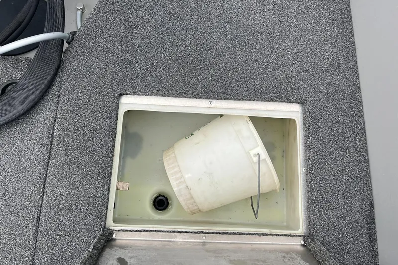 Slide: The Image of Storage compartment with a white bucket in a 2011 Lowe FM 165 boat. - 21
