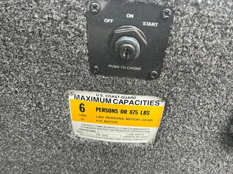 Slide: The Image of Boat control panel with U.S. Coast Guard capacity label, Lowe FM 165, 2011 model. - 26