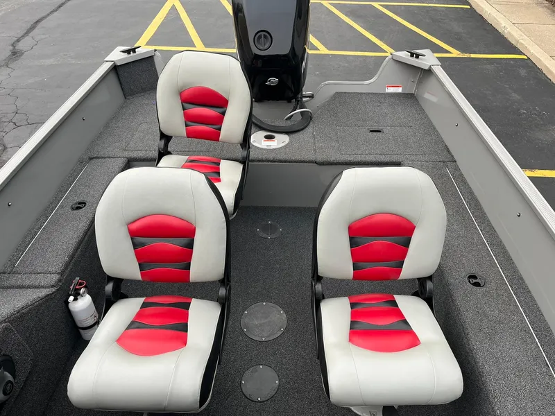 Slide: The Image of 2011 Lowe FM 165 boat interior with red and gray seats, parked on asphalt. - 8