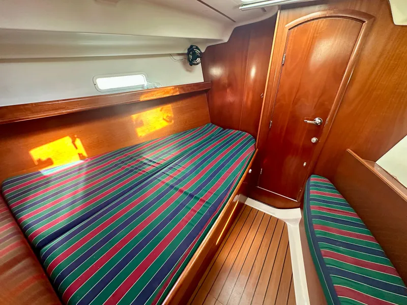 Slide: The Image of Beneteau Oceanis Clipper 393 cabin interior, 2002 model, featuring striped bedding and wooden finishes. - 29