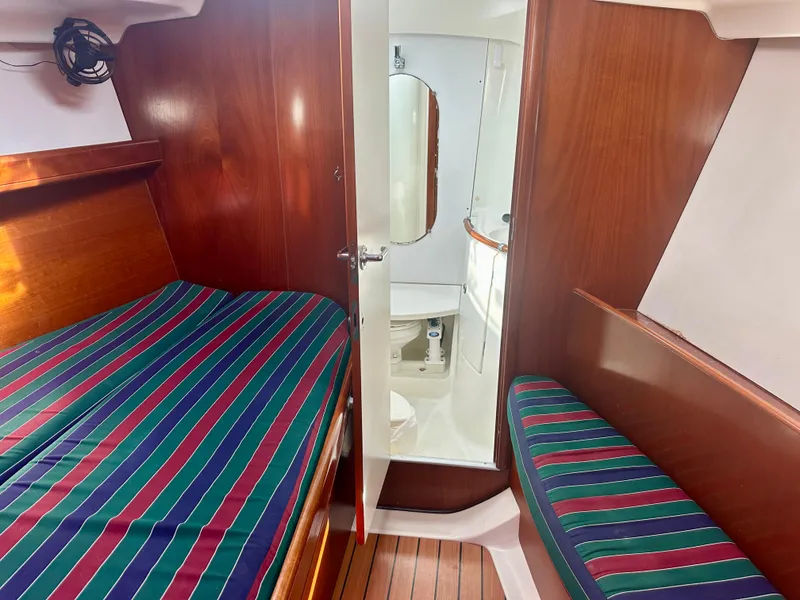 Slide: The Image of Interior cabin of 2002 Beneteau Oceanis Clipper 393 with striped bedding and wooden finish. - 30