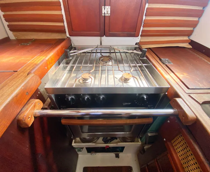 Slide: The Image of 1975 Whitby 42 Center Cockpit galley with stainless steel stove and wooden cabinetry. - 14