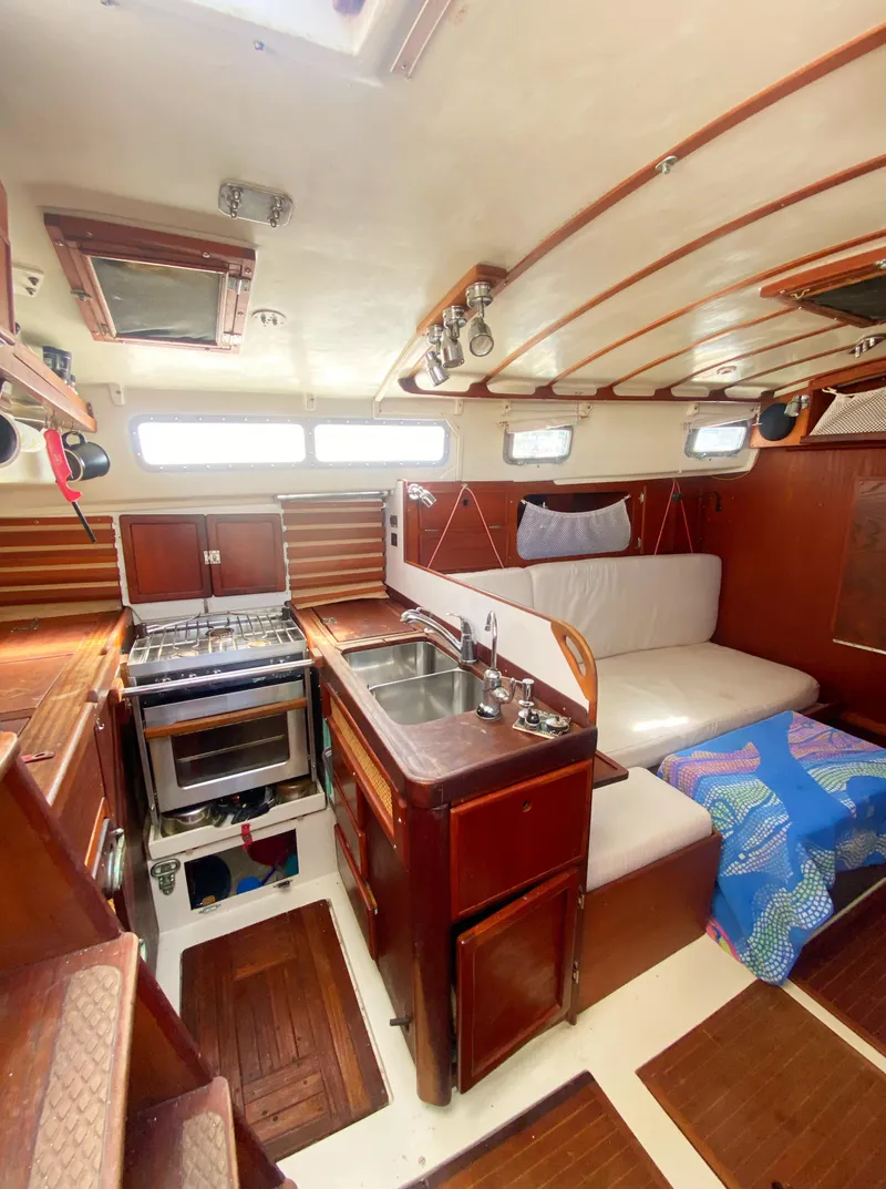 Slide: The Image of 1975 Whitby 42 Center Cockpit interior with kitchen, seating, and wood finish. - 20