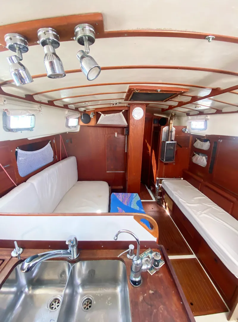 Slide: The Image of 1975 Whitby 42 Center Cockpit interior with wood finish, seating, and kitchen sink. - 21