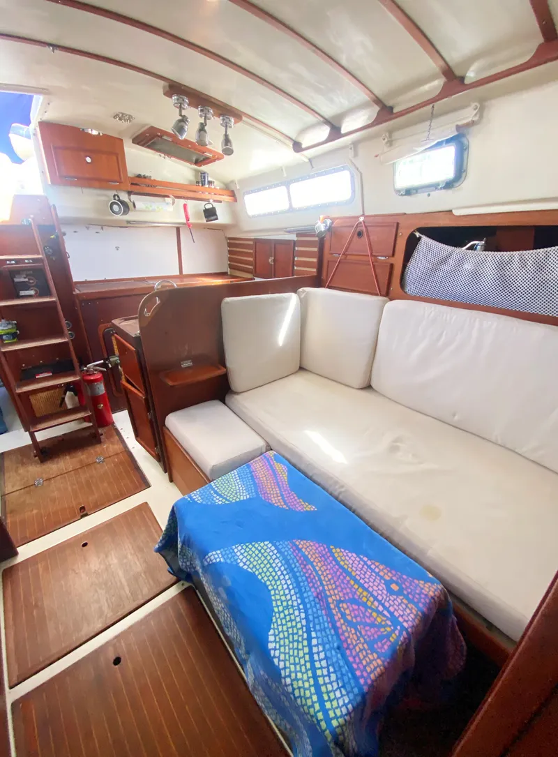 Slide: The Image of 1975 Whitby 42 Center Cockpit interior with white seating and wooden accents. - 23