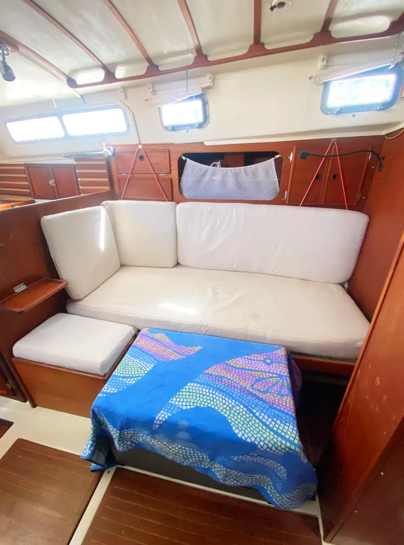 Slide: The Image of Interior of 1975 Whitby 42 Center Cockpit with white seating and blue-patterned tablecloth. - 25