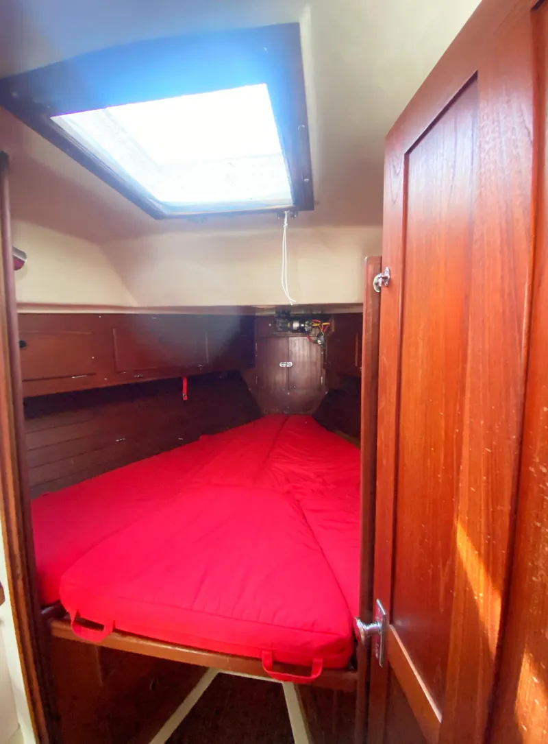 Slide: The Image of 1975 Whitby 42 Center Cockpit cabin with red bedding and wooden interior. - 26