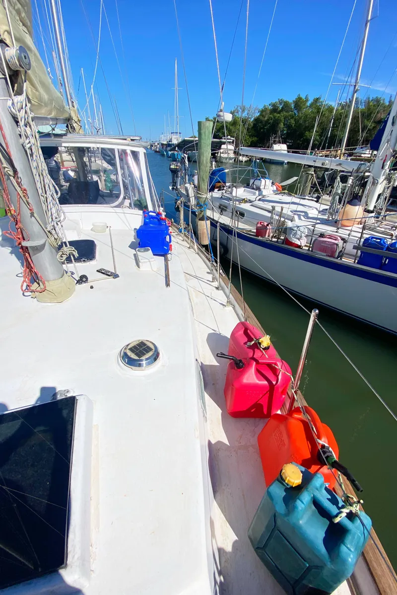Slide: The Image of 1975 Whitby 42 Center Cockpit sailboat docked, with colorful fuel containers on deck. - 3