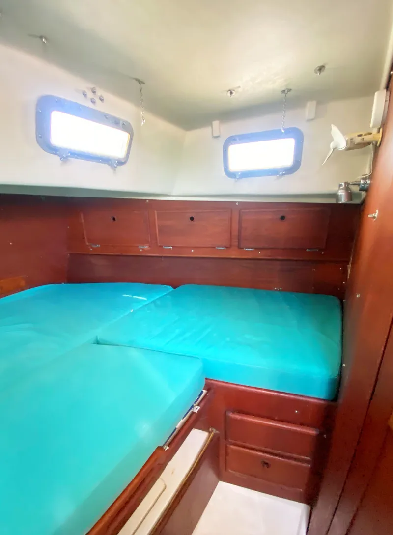 Slide: The Image of 1975 Whitby 42 Center Cockpit cabin with teal cushions and wooden storage cabinets. - 30