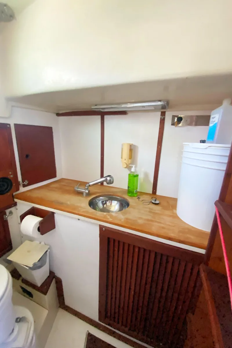 Slide: The Image of 1975 Whitby 42 Center Cockpit bathroom with sink, wooden cabinetry, and storage. - 34