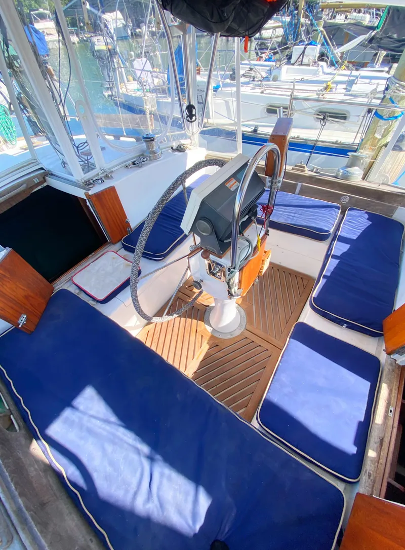 Slide: The Image of 1975 Whitby 42 Center Cockpit with blue cushions and wooden flooring in marina setting. - 8