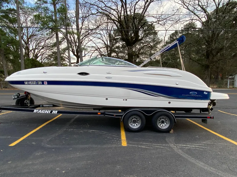 Slide: The Image of 2005 Chaparral Sunesta 254 boat on trailer in parking lot, surrounded by trees. - 0