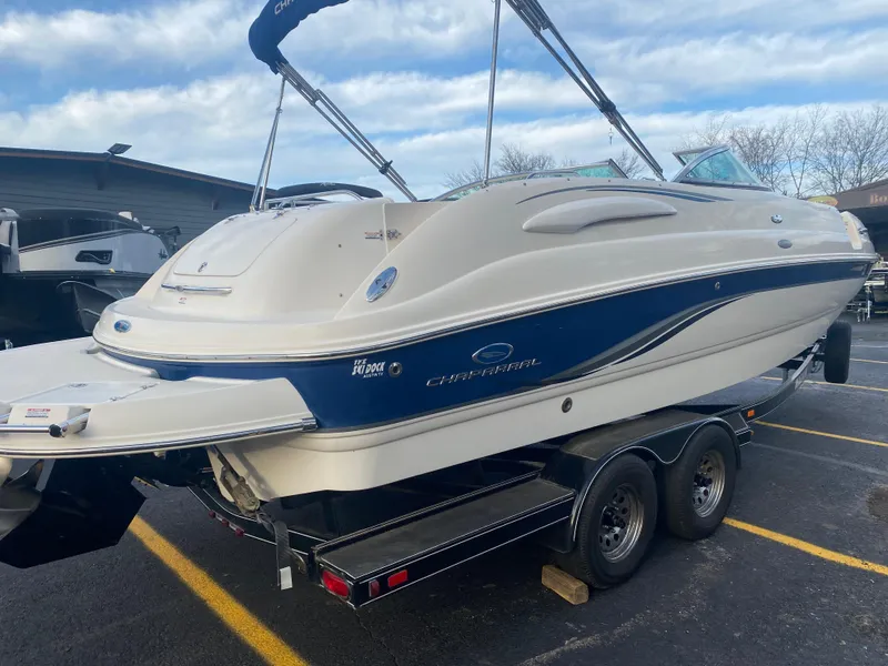 Slide: The Image of 2005 Chaparral Sunesta 254 boat on trailer, white and blue design, parked outdoors. - 1