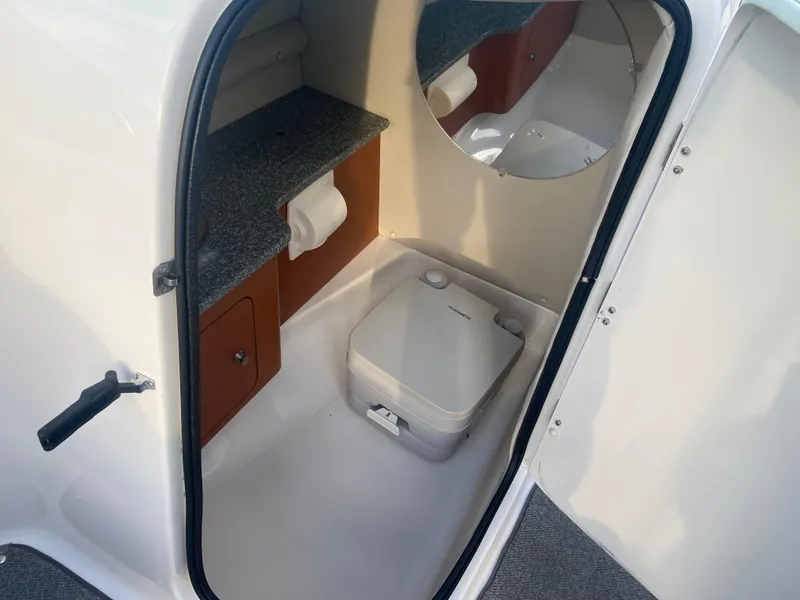 Slide: The Image of 2005 Chaparral Sunesta 254 boat interior with compact toilet and storage. - 23