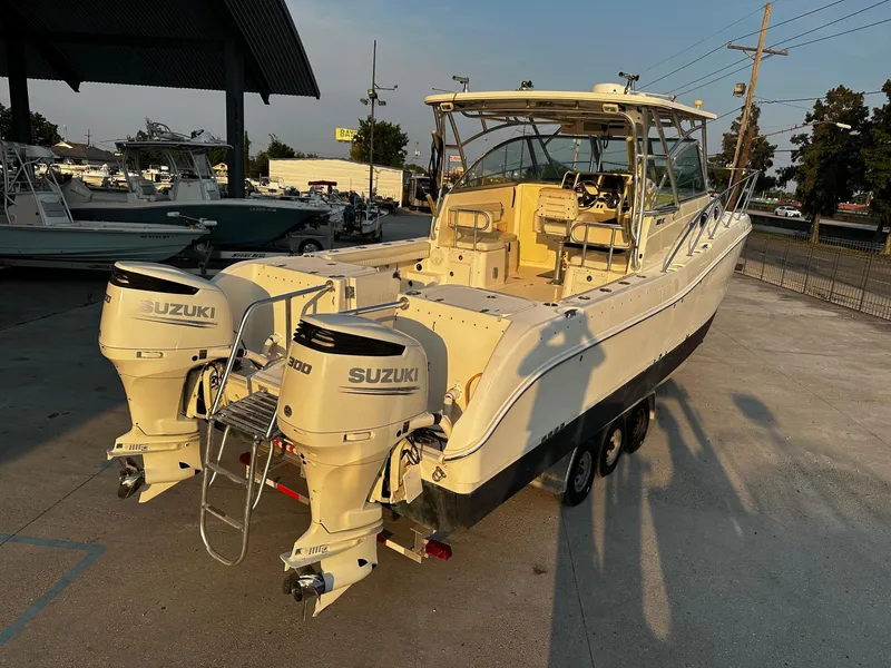 Slide: The Image of 2005 World Cat 320EC boat with dual Suzuki 300 engines, parked outdoors. - 13