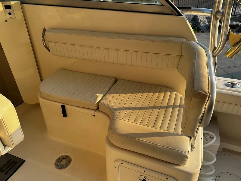 Slide: The Image of 2005 World Cat 320EC boat interior seating with beige upholstery and storage compartment. - 19