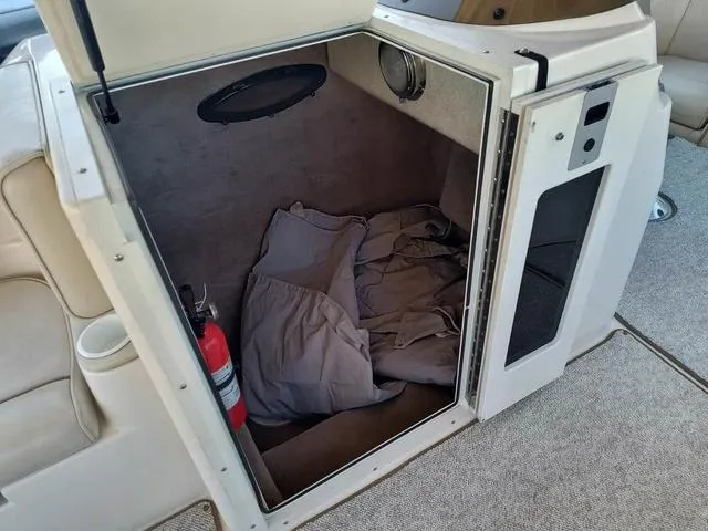 Slide: The Image of 1998 Ebbtide 2300 Mystique Deck Boat interior storage with fire extinguisher and fabric. - 11