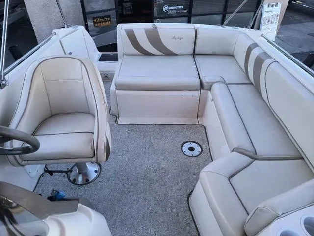 Slide: The Image of 1998 Ebbtide 2300 Mystique Deck Boat interior with beige seating and steering chair. - 15