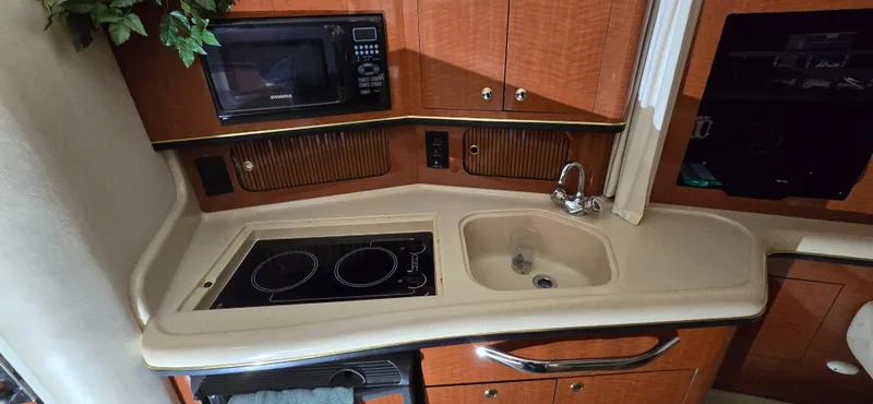 Slide: The Image of 2002 Sea Ray 300 Sundancer galley with stove, sink, and microwave. - 28