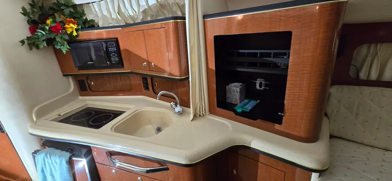 Slide: The Image of Interior of a 2002 Sea Ray 300 Sundancer boat, featuring a compact kitchen area. - 29