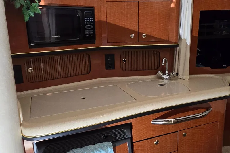 Slide: The Image of 2002 Sea Ray 300 Sundancer kitchen with sink, microwave, and wooden cabinetry. - 31