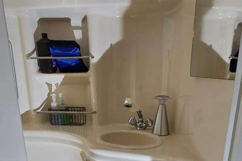 Slide: The Image of 2002 Sea Ray 300 Sundancer bathroom with sink, mirror, and storage shelves. - 40