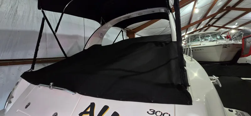 Slide: The Image of 2002 Sea Ray 300 Sundancer boat with black cover in storage. - 8