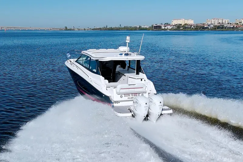 Slide: The Image of 2021 Regal 36 XO boat cruising on a calm lake with twin engines. - 12