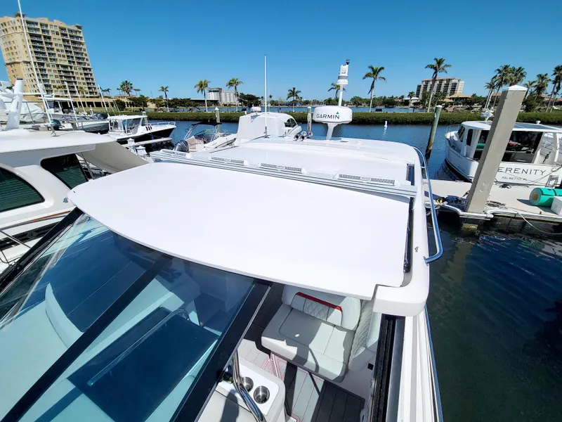 Slide: The Image of 2021 Regal 36 XO boat docked in marina with palm trees and buildings in background. - 46