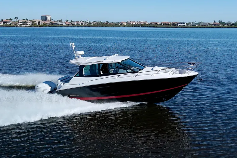 Slide: The Image of 2021 Regal 36 XO boat cruising on a calm lake with a scenic shoreline. - 8