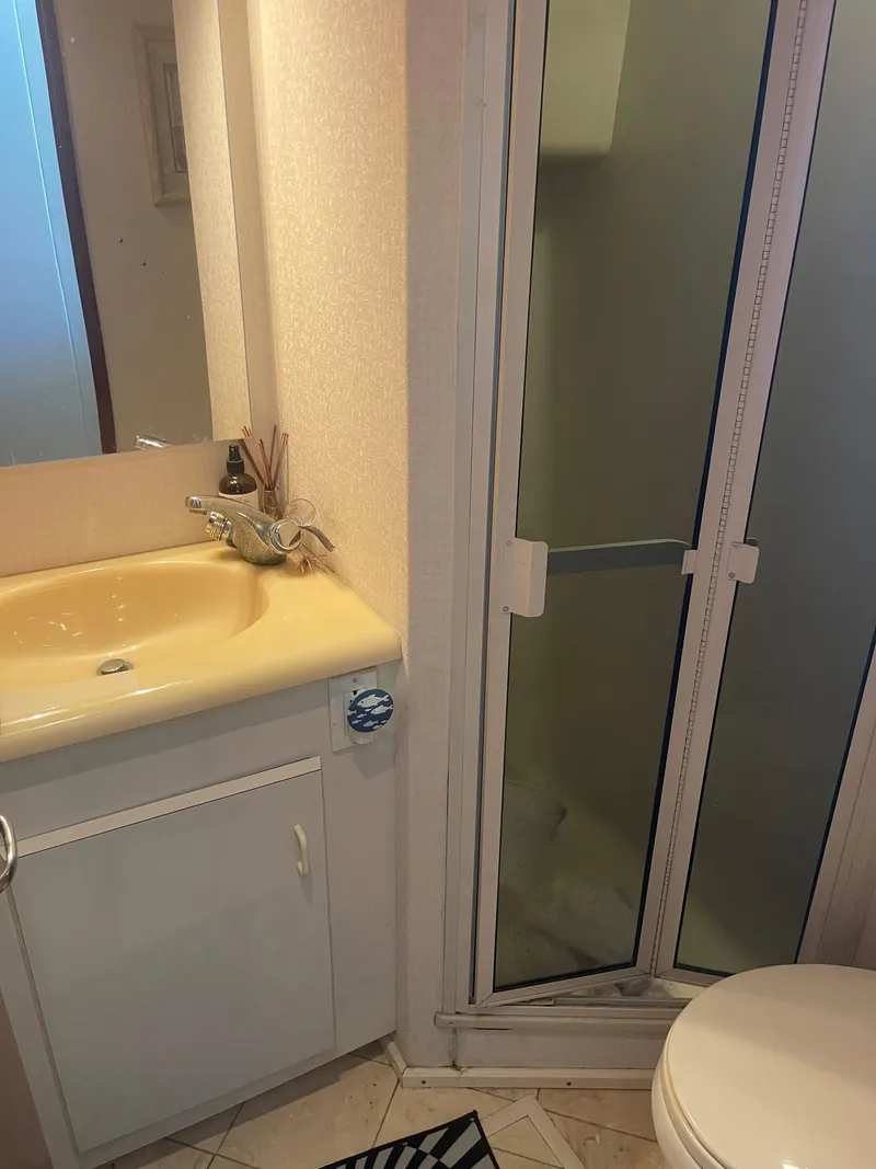 Slide: The Image of Compact bathroom in a 1999 Viking 58 EB yacht with shower, sink, and toilet. - 22