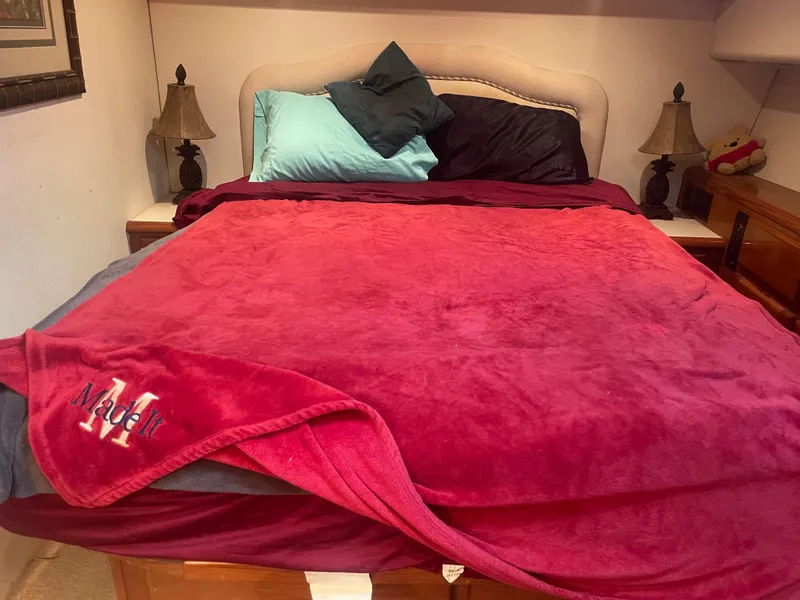 Slide: The Image of Cozy bedroom with red blanket, colorful pillows, and bedside lamps in a 1999 Viking 58 EB. - 26