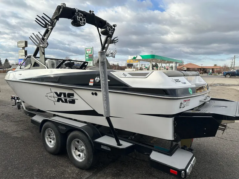 Slide: The Image of 2016 Axis Boats T22 on trailer, parked near a gas station under cloudy skies. - 6