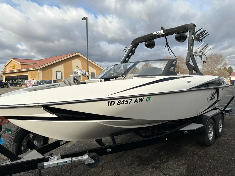 Slide: The Image of 2016 Axis Boats T22 on trailer, parked near a store under cloudy skies. - 8