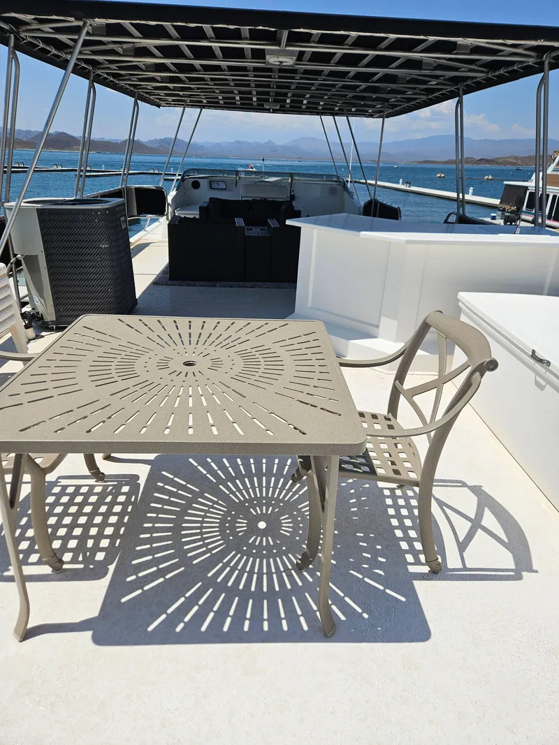 Slide: The Image of Rooftop deck of 1997 Sumerset Houseboat with metal table and chairs, overlooking serene waters. - 10