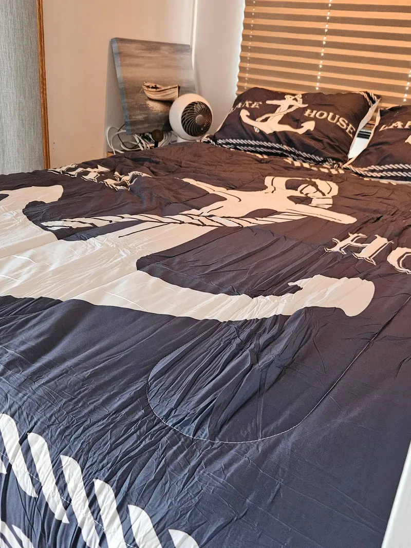 Slide: The Image of Nautical-themed bedding on a 1997 SUMERSET HOUSEBOATS houseboat, featuring anchor design and decorative pillows. - 12