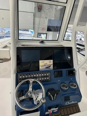 Slide: The Image of 2024 Tidewater 272 CC Adventure boat dashboard with steering wheel and controls. - 13
