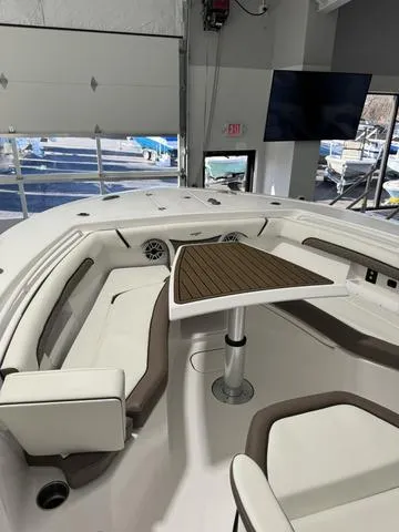 Slide: The Image of 2024 Tidewater 272 CC Adventure boat interior with seating and table in showroom. - 17