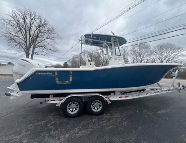 Slide: The Image of 2024 Tidewater 272 CC Adventure boat on trailer, blue hull, overcast sky. - 5