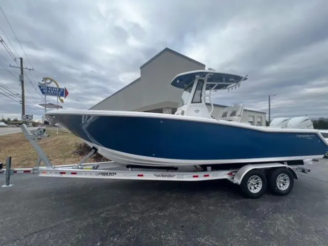 Slide: The Image of 2024 Tidewater 272 CC Adventure boat on trailer, blue hull, parked outdoors. - 7