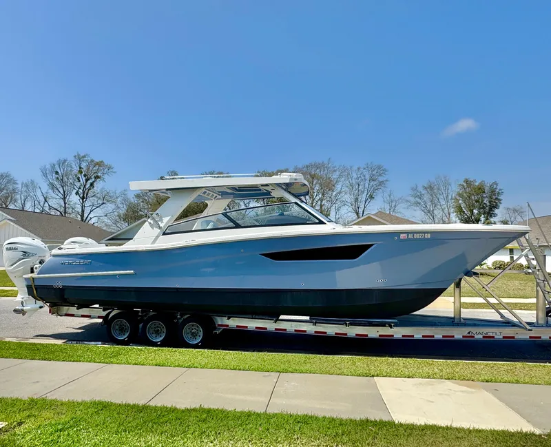Slide: The Image of 2022 World Cat 400 DC-X boat on trailer, parked outdoors under clear blue sky. - 1
