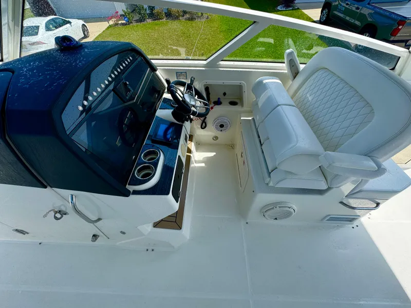 Slide: The Image of 2022 World Cat 400 DC-X boat cockpit with steering wheel and white seating. - 13