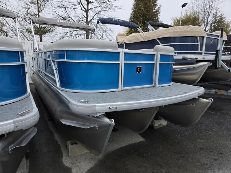 Slide: The Image of 2025 Godfrey Xperience 2286 SBX pontoon boat with blue exterior, docked outdoors. - 2