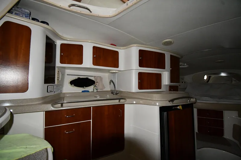 Slide: The Image of 2001 Chris-Craft 328 Express Cruiser interior with wooden cabinets and compact kitchen area. - 30