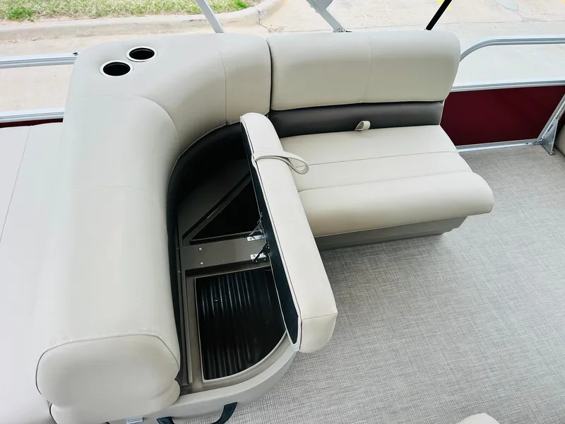 Slide: The Image of 2025 Sun Tracker Party Barge 18 DLX interior with beige seating and storage compartment. - 26