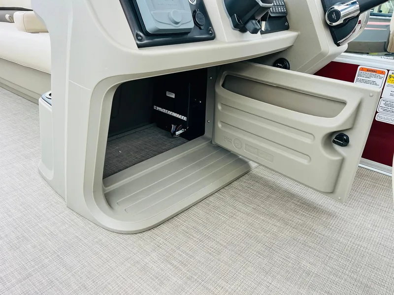 Slide: The Image of 2025 Sun Tracker Party Barge 18 DLX storage compartment with open door on beige interior. - 38
